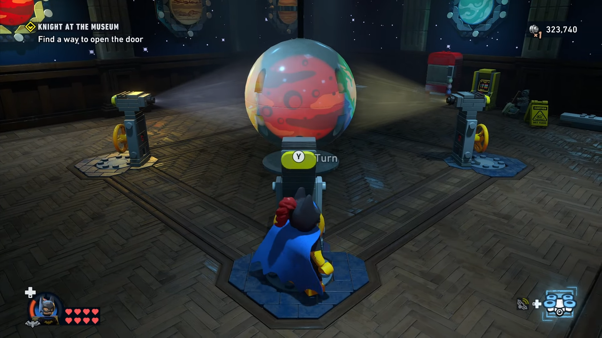 Character turns the mechanism to cycle through the planets to Mars in Knight at the Museum mission in Lego Batman: Legacy of the Dark Knight.