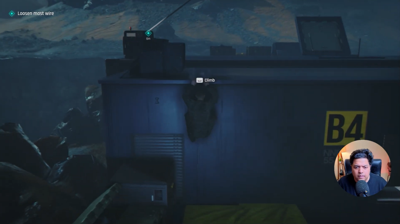 James Bond hanging from the edge of a B4 building rooftop while climbing toward the mast support cable objective in 007 First Light.