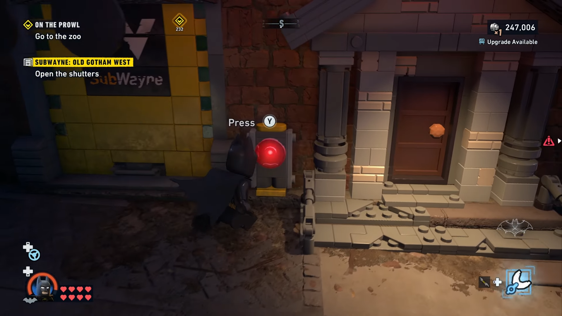 Batman pressing the red button to open the shutters to Subwayne at Old Gotham West in Lego Batman: Legacy of the Dark Knight